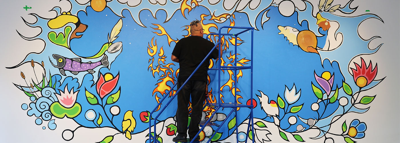 John Williams working on the mural in the lecture theatre at the Judith & Norman Alix Art Gallery.
