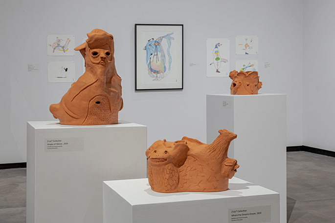 Three clay sculptures sitting on white pedestals