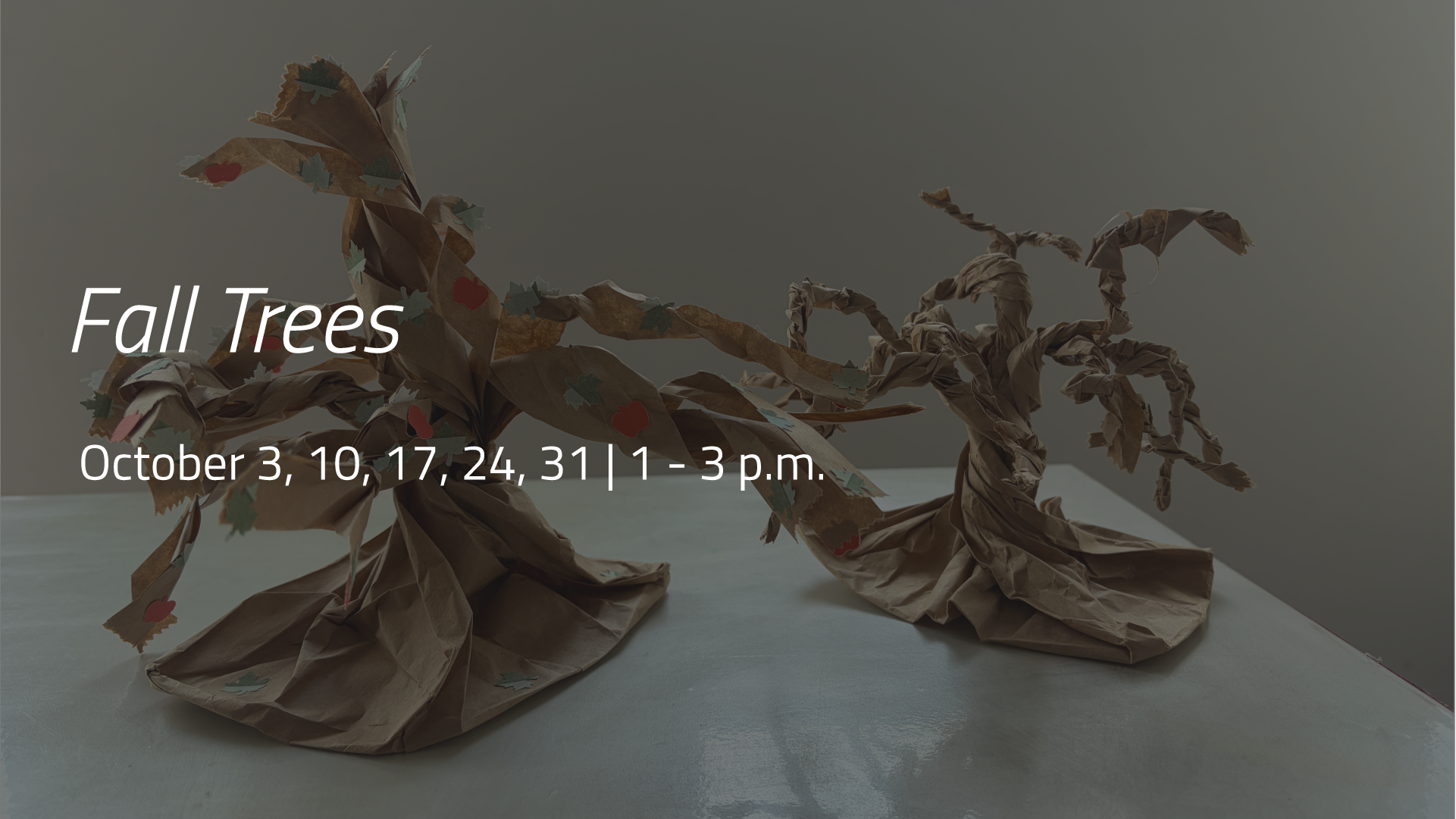 Two sculptural trees made from twisted brown paper displayed on a tabletop.
