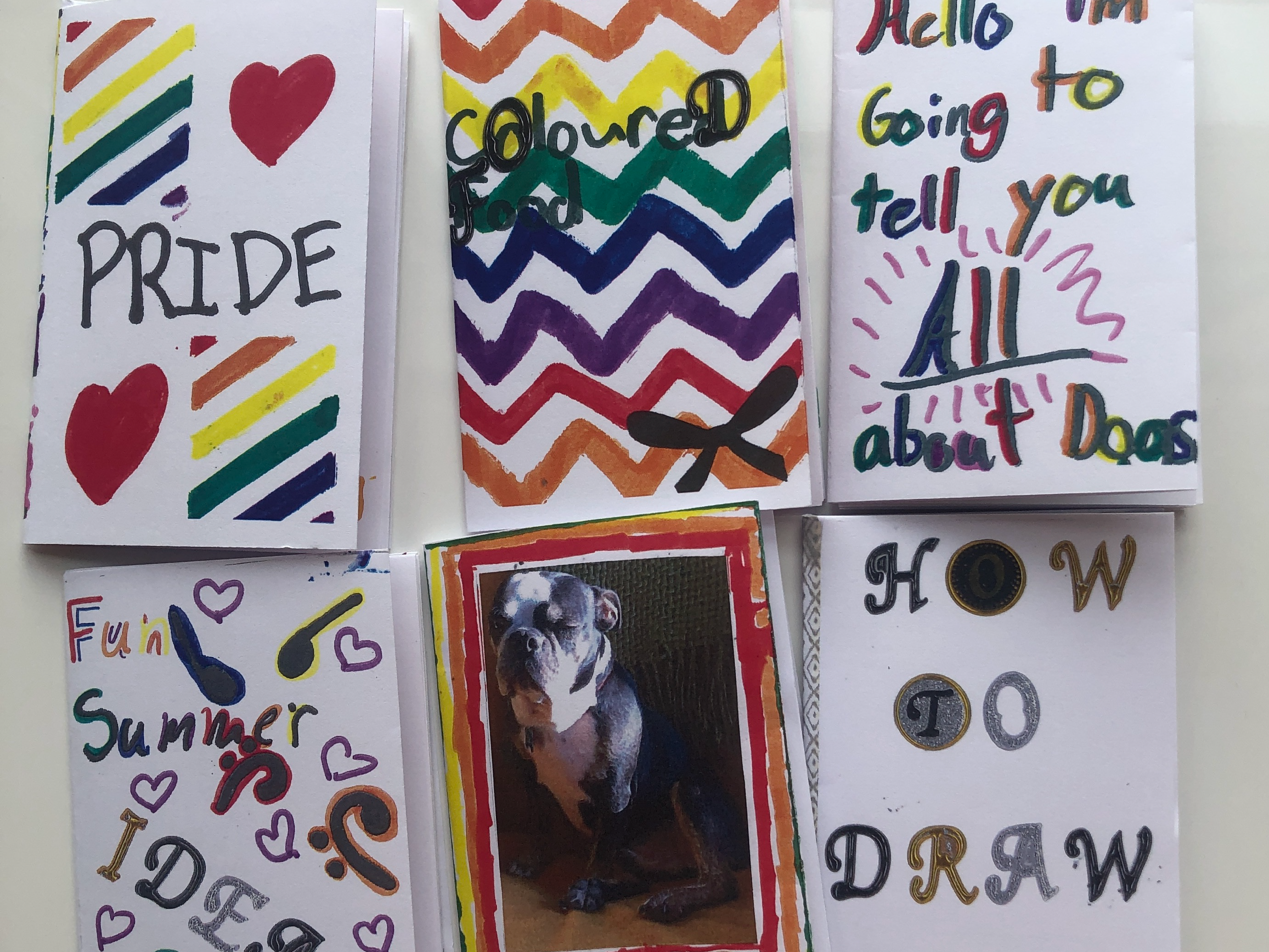 Handmade mini books decorated with colorful drawings, lettering, hearts, and a dog photograph.