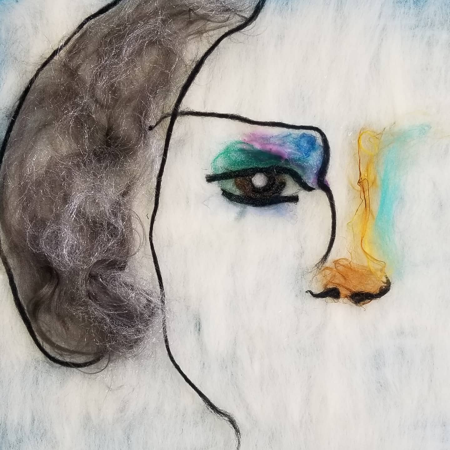 Fiber art picture of half a face with black hair