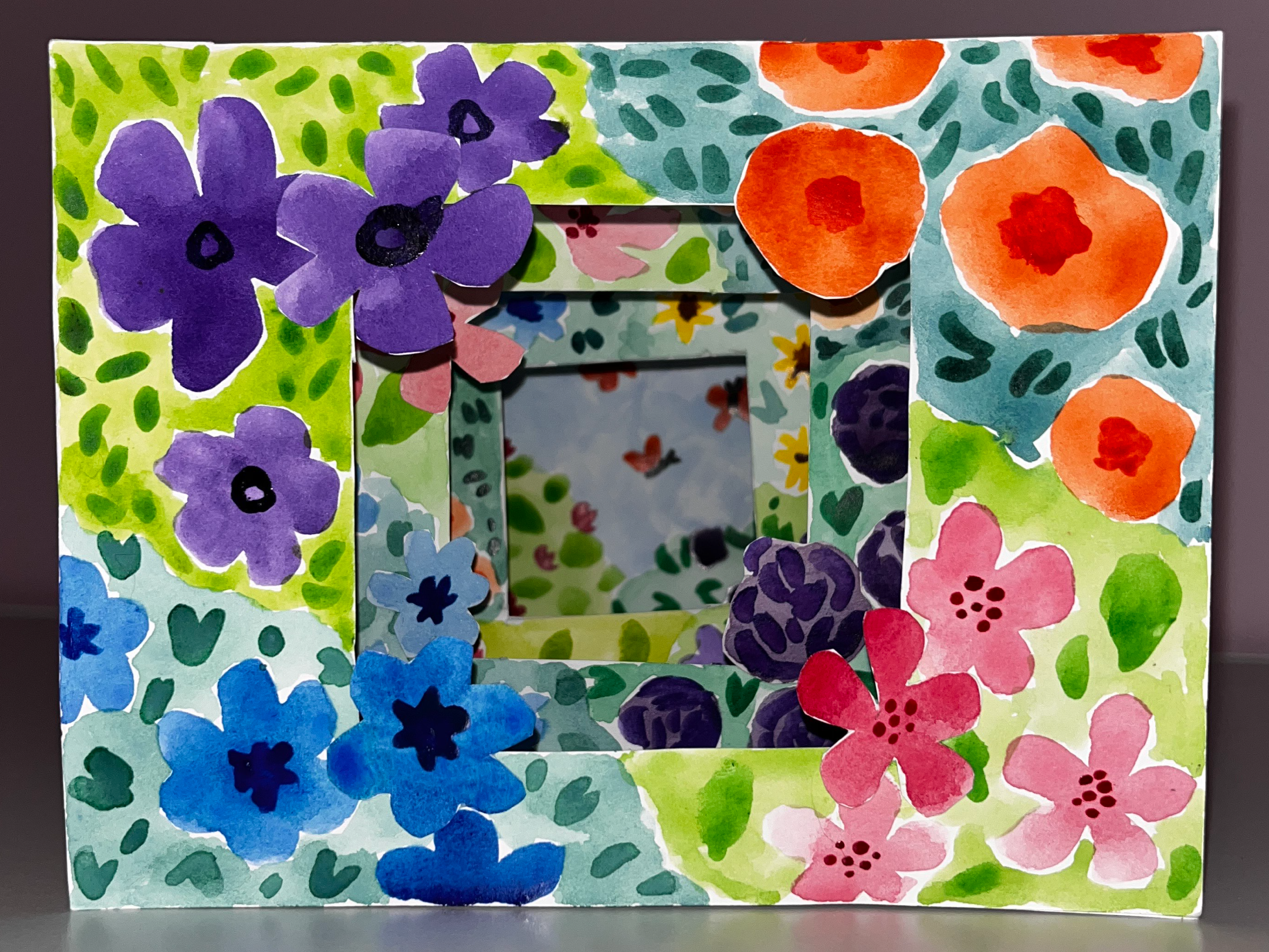 A water colour tunnel book depicting a flowery garden scene sits on a table.