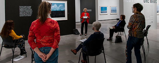 Woman standing in a gallery talking to a group of people