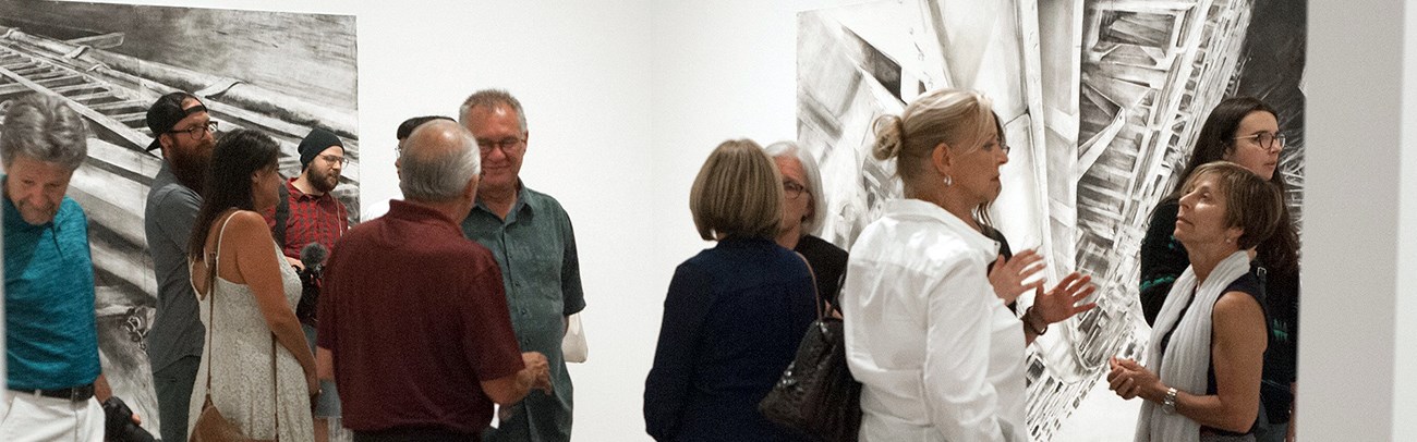 Group of people gathered in an art gallery for a members reception