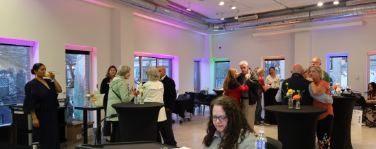 Various individuals stand in the lecture theatre at the Judith & Norman Alix Art Gallery, enjoying the members open event.