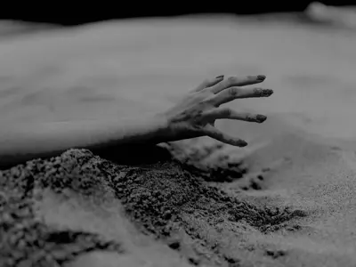 Stories In Focus overall winner. A hand reaches out through a mound of sand. The photo was taken in black and white.
